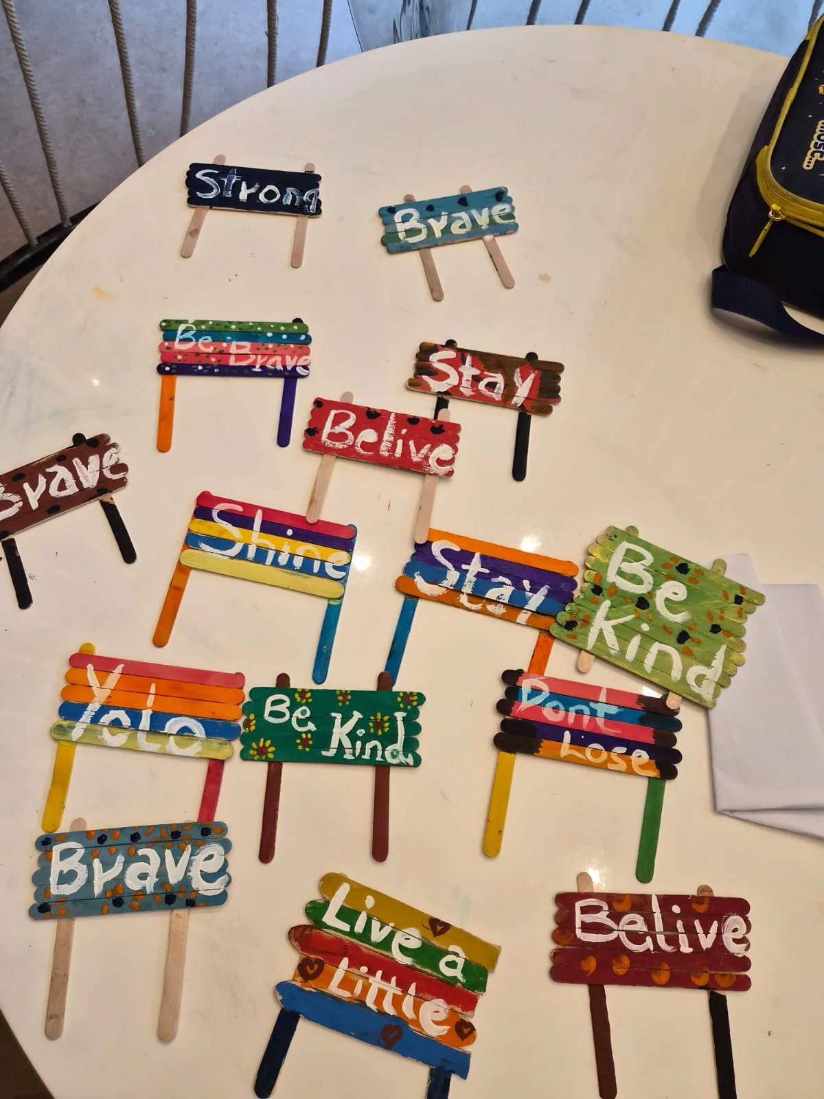 Hand-painted popsicle-stick signs reading Strong, Brave, Shine, Be Kind and other affirmations